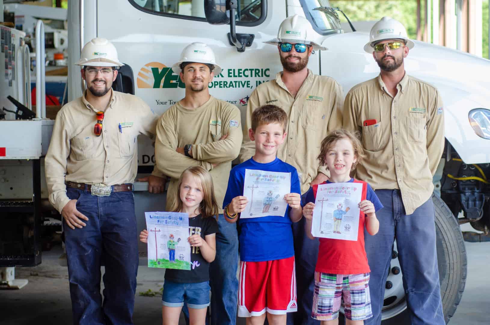 YEC coloring contest winners with lineworkers in front of utility truck