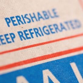 A close-up image of packaging with the text "PERISHABLE KEEP REFRIGERATED" in blue font, indicating that the contents must be kept cool.