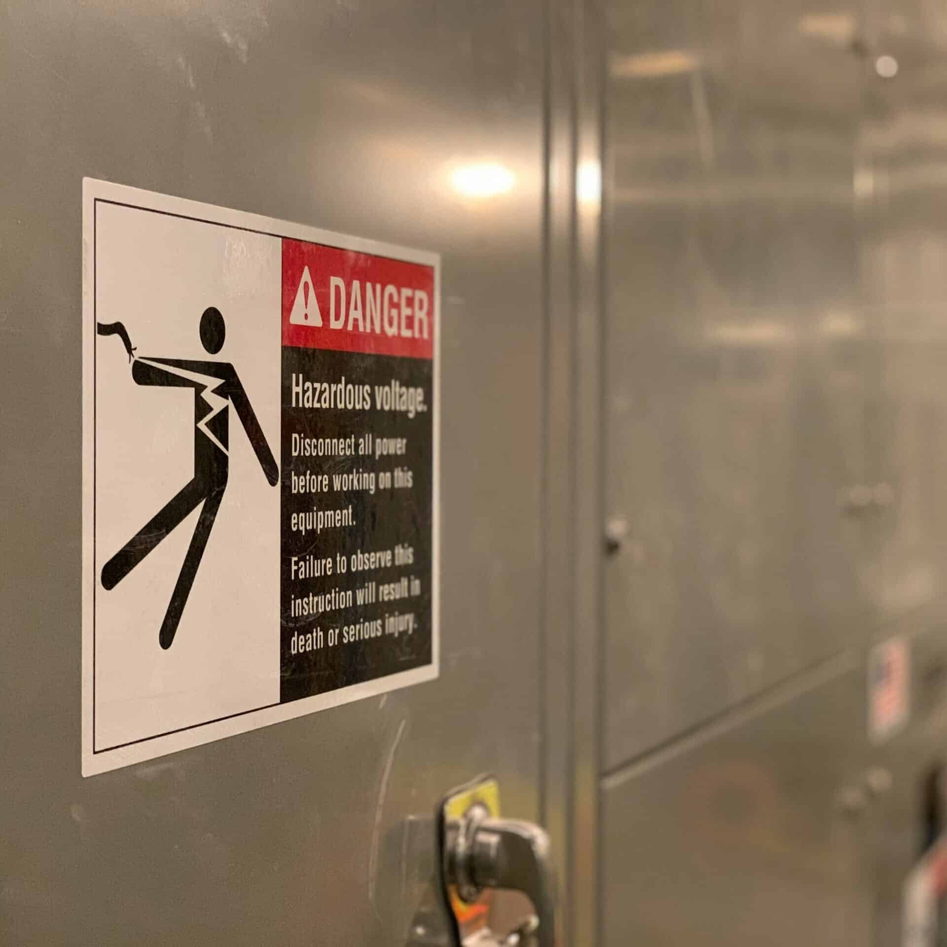 A cautionary "Danger" sign on a metal cabinet warns of hazardous voltage, emphasizing disconnecting power to avoid potential death or serious injury.