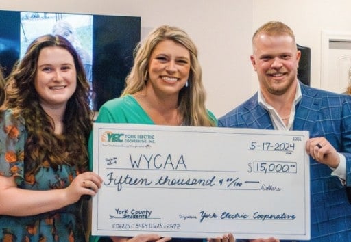 Women and men holding a large presentation check payable to WYCAA in the amount of fifteen thousand dollars