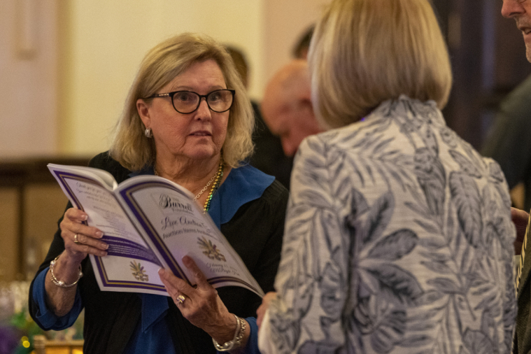 Two women study to the list of items up for auction.