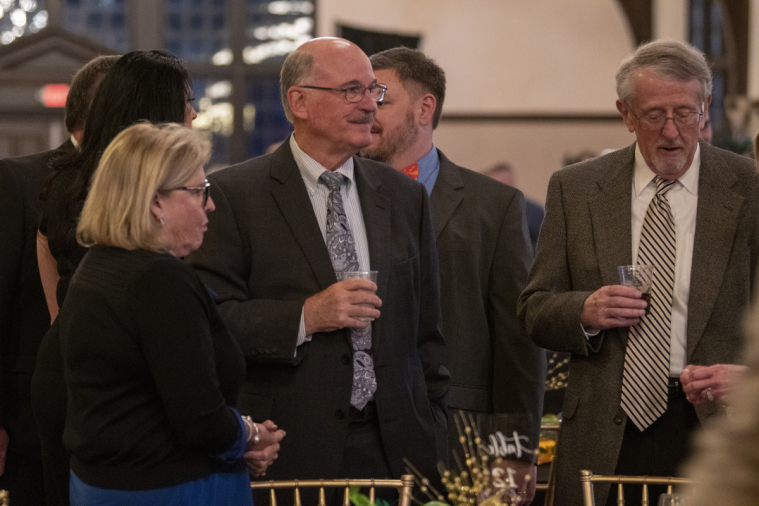 A trio of attendees chat and sip wine.