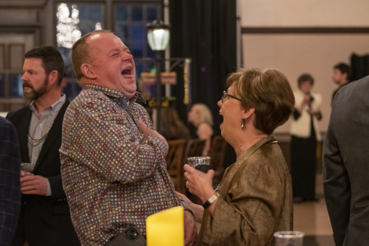 Two attendees share a joke and laugh uproariously.