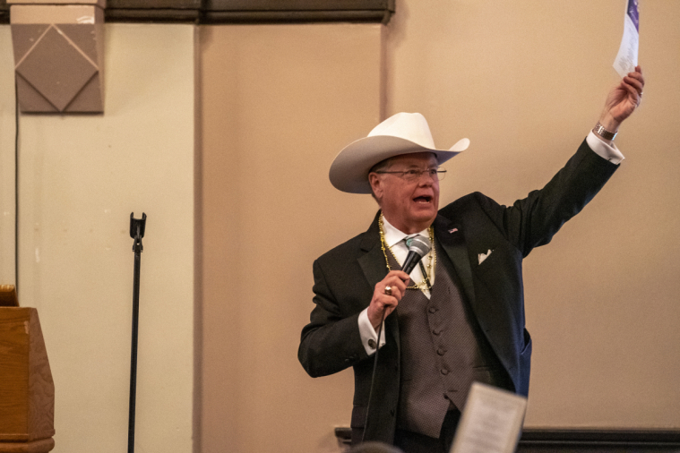 The auctioneer in a cowboy hat shouts out to the crowd.