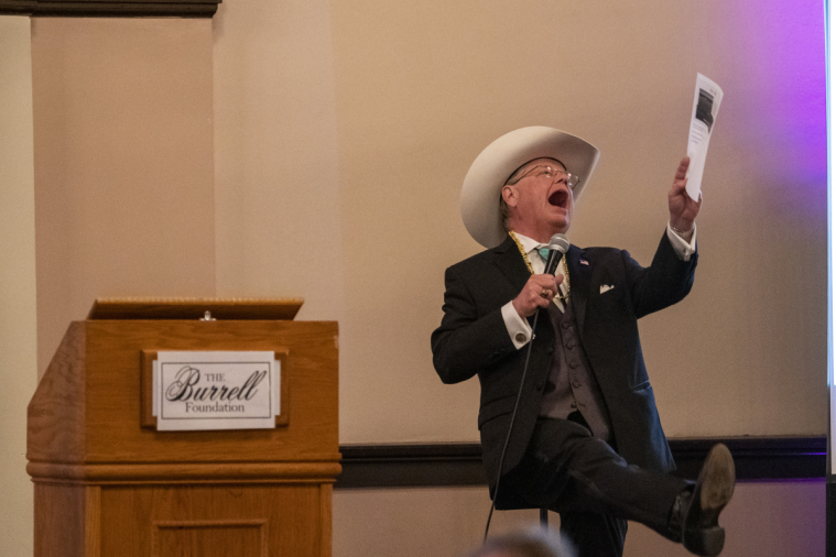 The auctioneer has a great time, kicking up his heels.