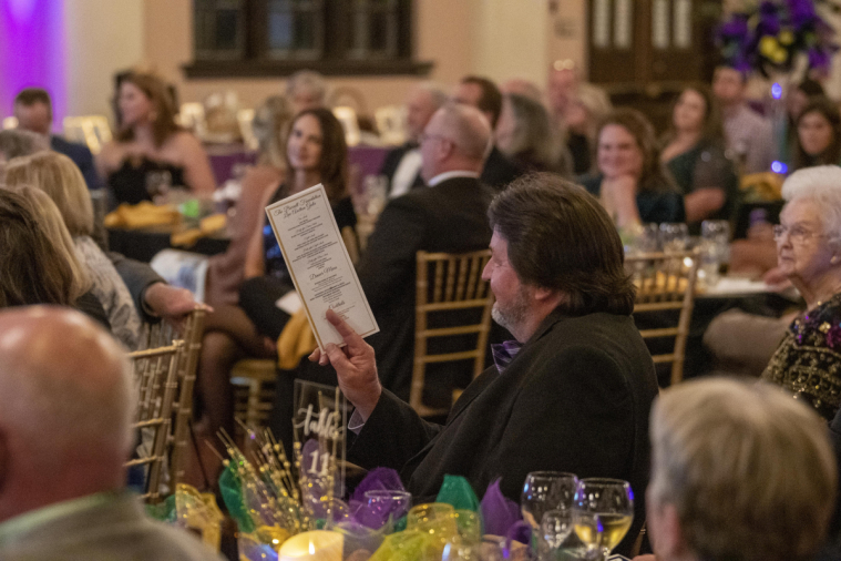 An audience member signals to the auctioneer that he wants to bid.