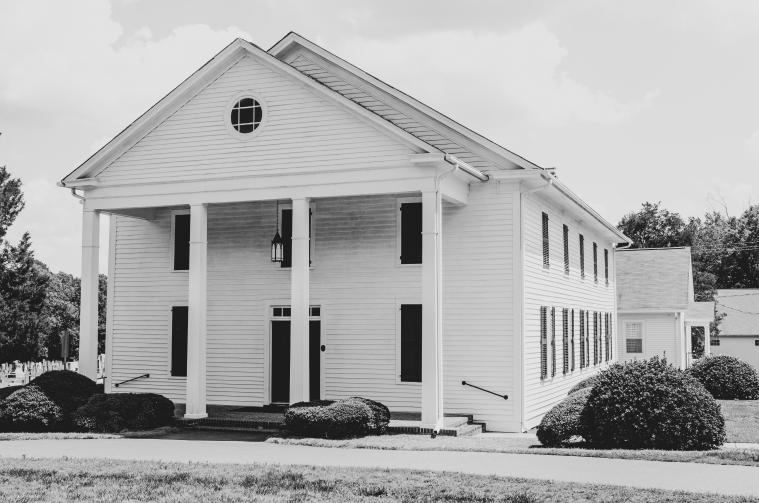 A white clapboard country church is pictured in black and white.