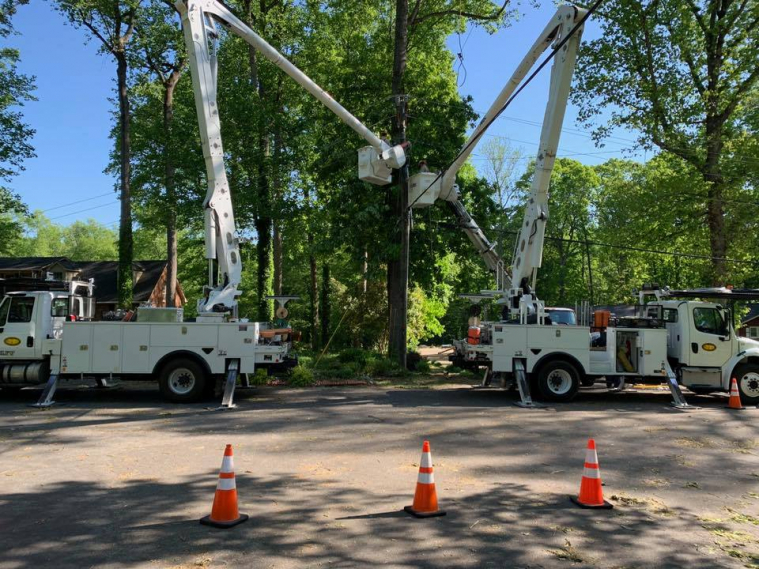 Two basket crane trucks backed up to a utility pole