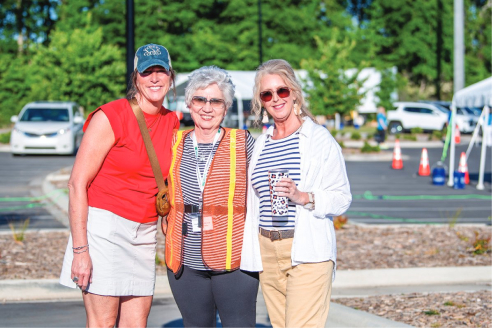 An employee poses for a photo with two members