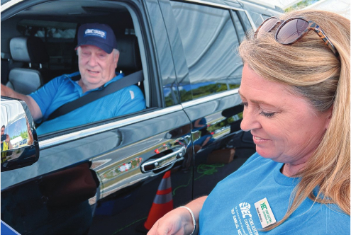 A worker helps out while a member smiles for the camera