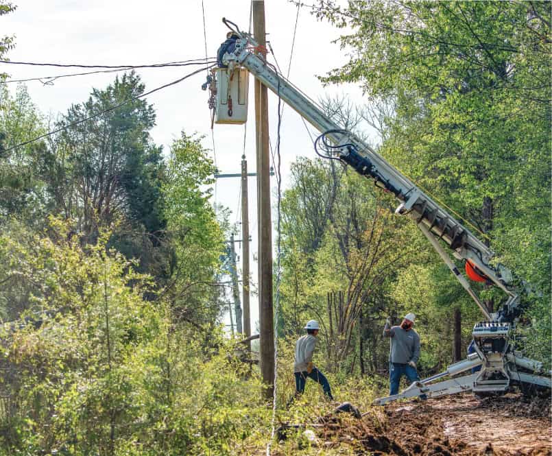 Linemen are seen working to clear overgrown trees